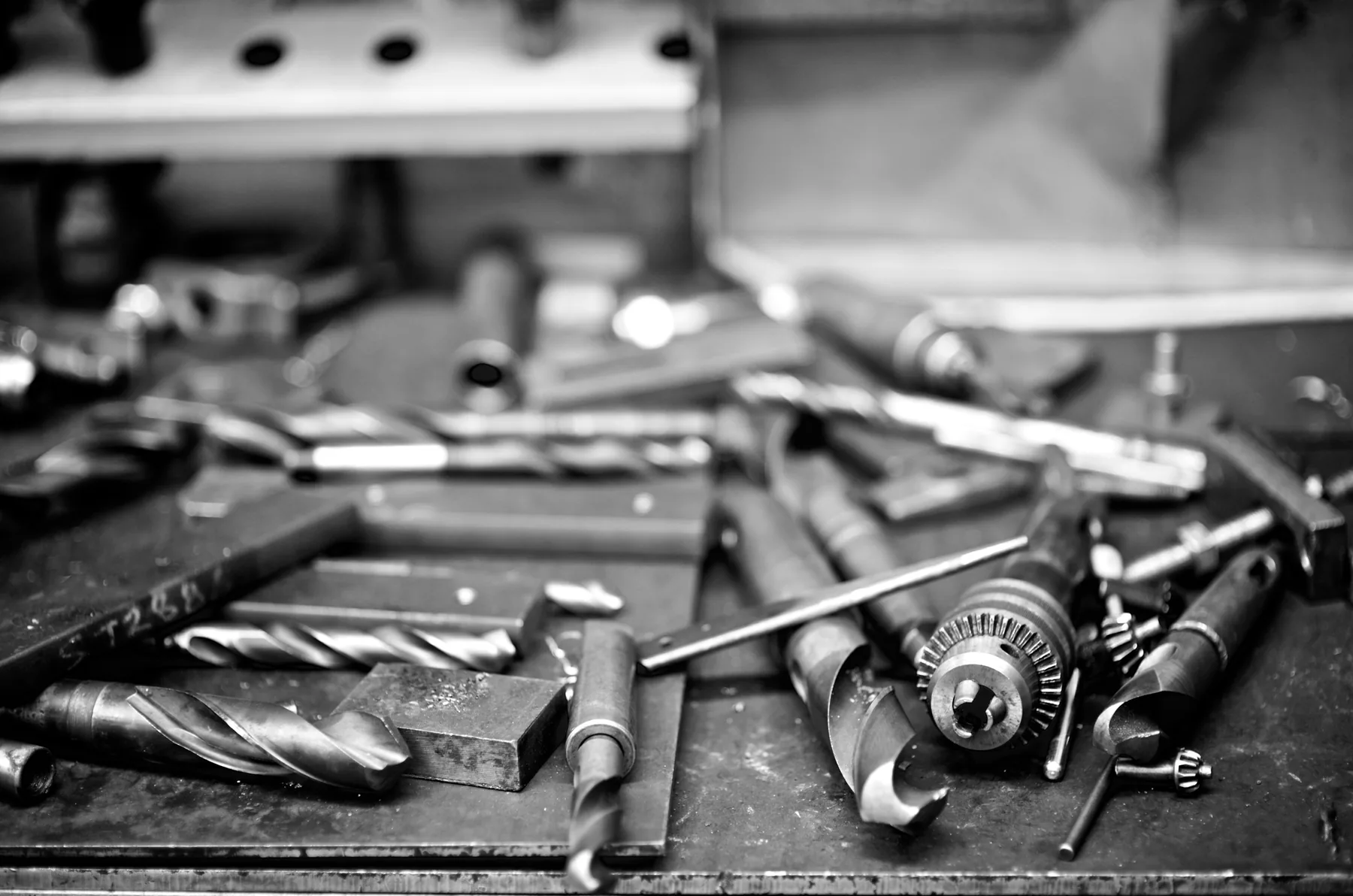 Drill bits and well-used tools scattered across a metal workshop bench.